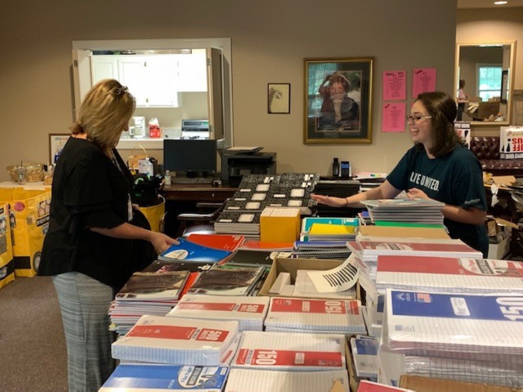 Volunteers sorting donations and packing backpacks