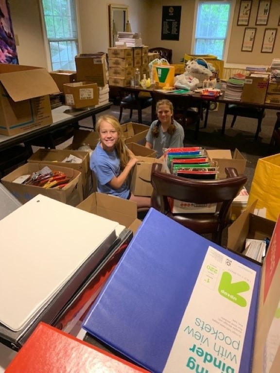 Volunteers sorting donations and packing backpacks