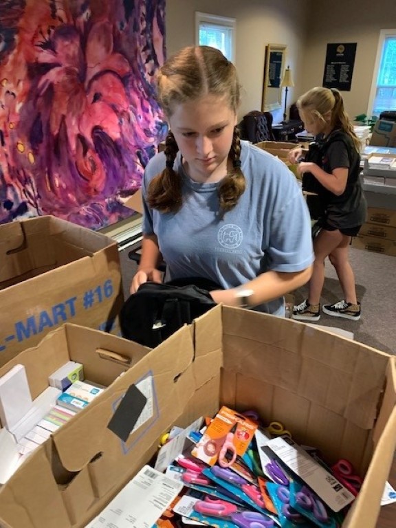 Volunteers sorting donations and packing backpacks