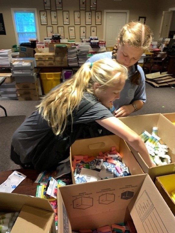 Volunteers sorting donations and packing backpacks