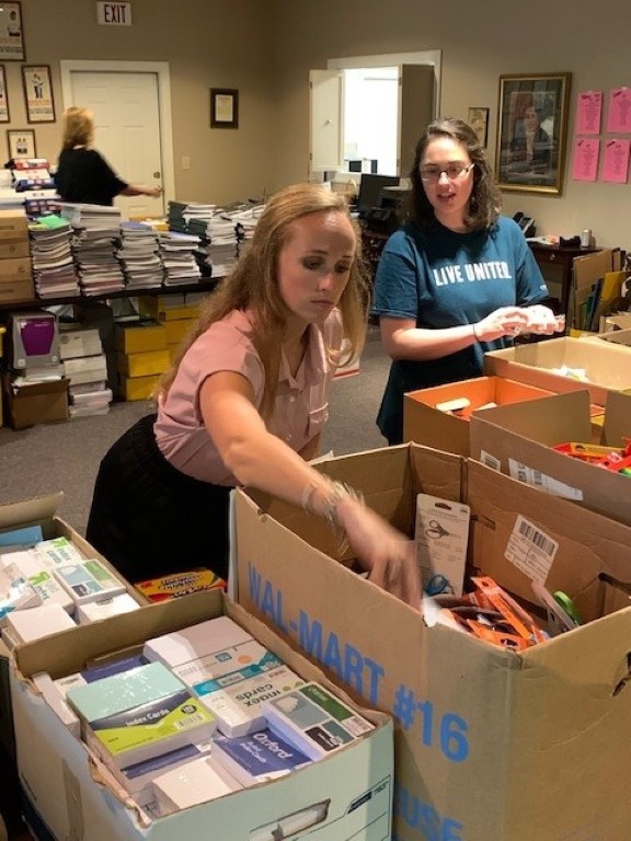 Volunteers sorting donations and packing backpacks