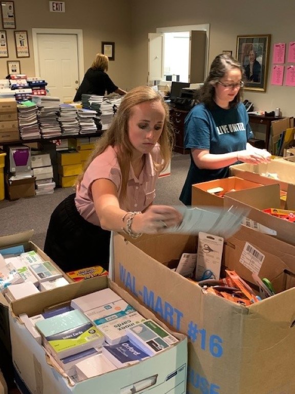 Volunteers sorting donations and packing backpacks