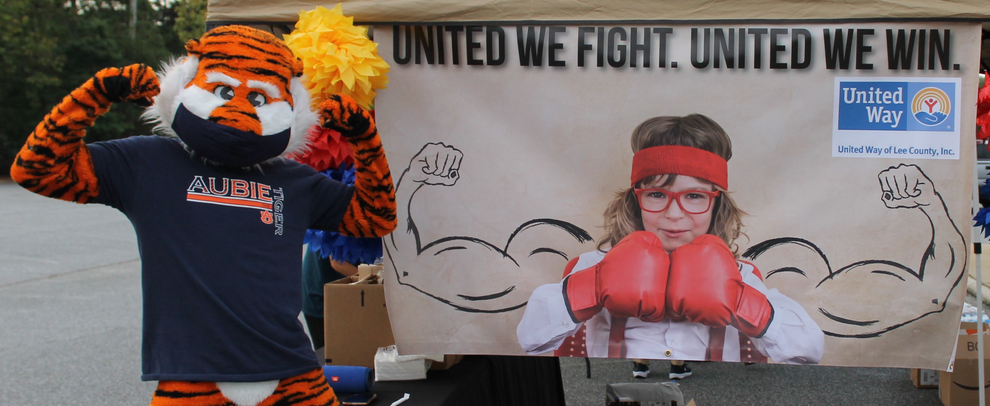 Aubie posing next to a campaign banner