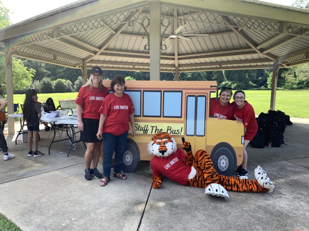 Aubie and volunteers posing in front of school bus cutout