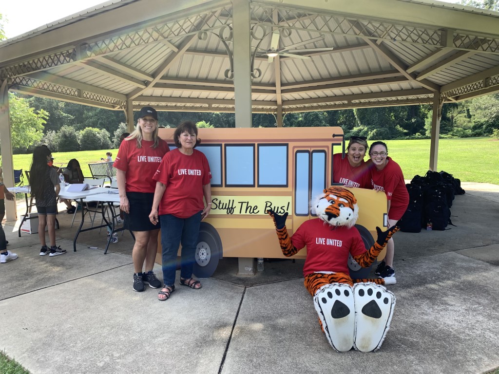 Aubie and volunteers posing in front of school bus cutout