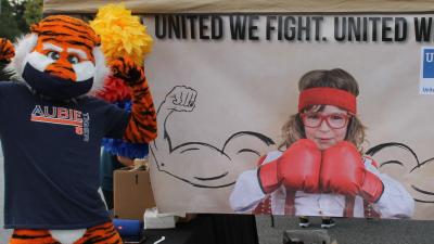 Aubie posing next to a campaign banner