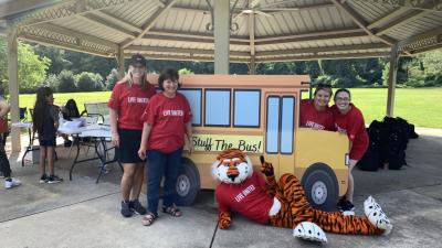 Aubie and volunteers posing in front of school bus cutout